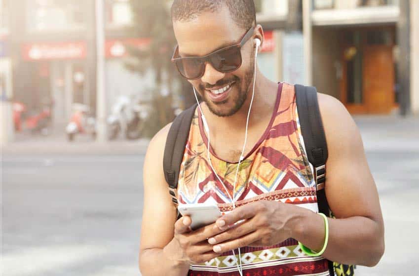 Young man using music production app on his phone while he walks