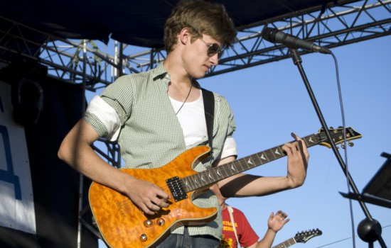 Young male guitarist performing live on outdoor concert stage