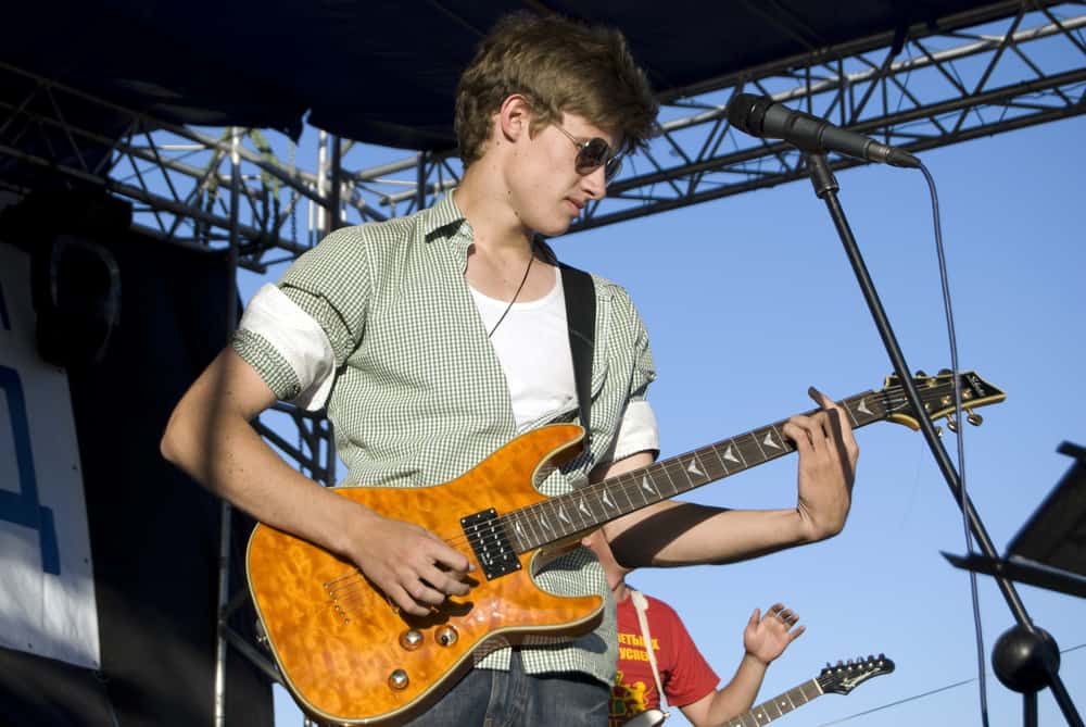 Young male guitarist performing live on outdoor concert stage