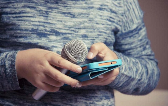 Young singer with microphone and musically app on phone