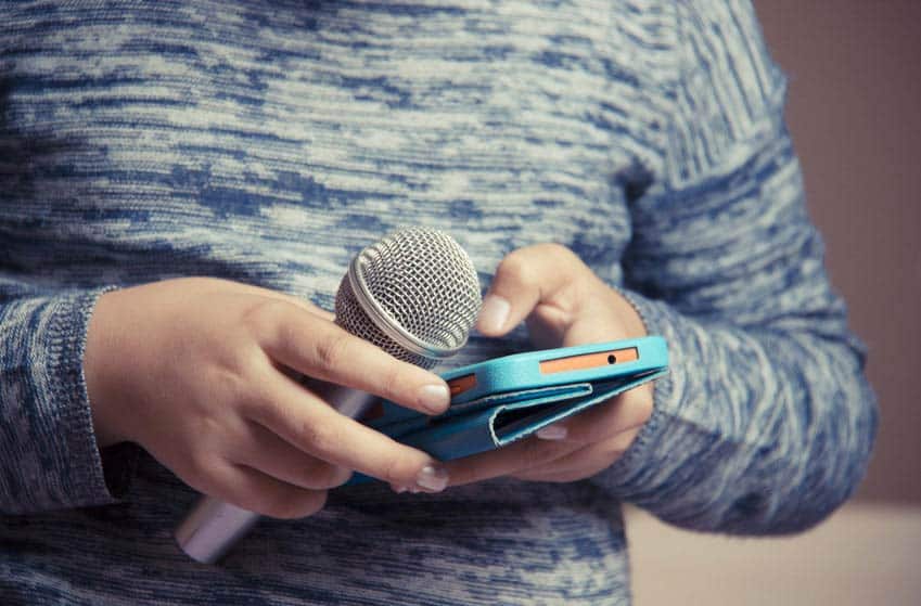 Young singer with microphone and musically app on phone