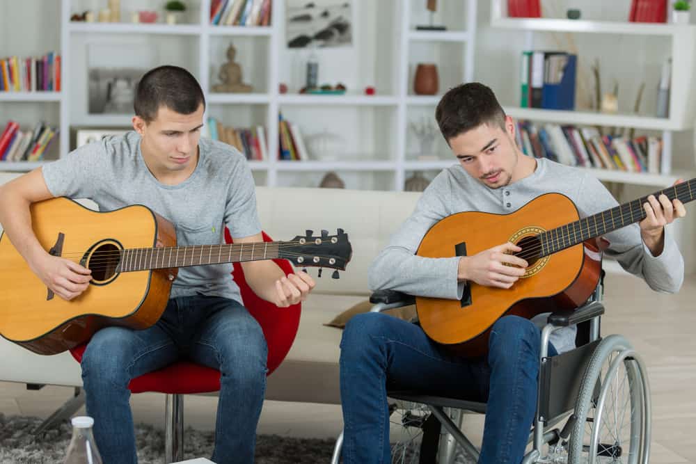 Music therapist playing guitar alongside client in wheelchair