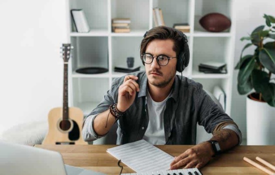 Male musician learning music online with keyboard and laptop