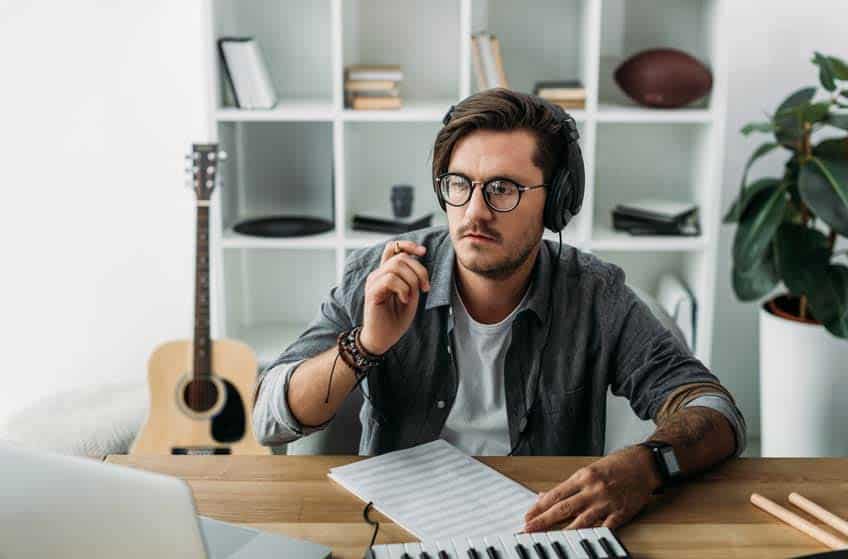 Male musician learning music online with keyboard and laptop