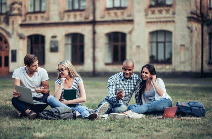 Four music department students sitting on the lawn of their college campus