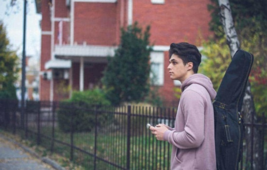 Music education student walking through campus with his guitar