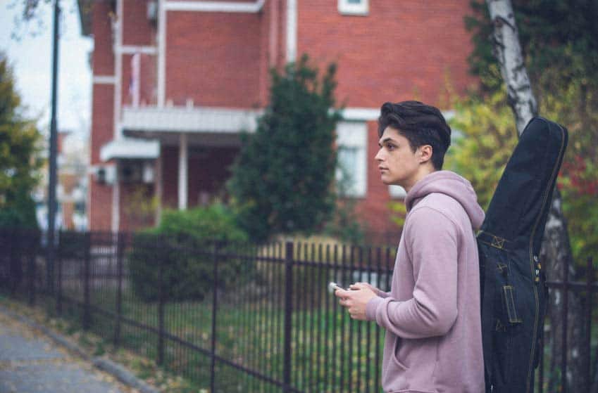 Music education student walking through campus with his guitar