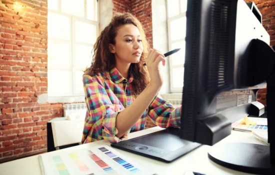 Poster artist using her computer and stylus to create a design
