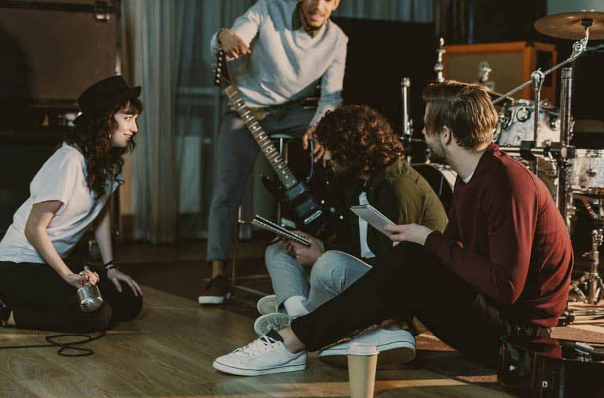 Four young musicians hanging out in practice space with musical gear