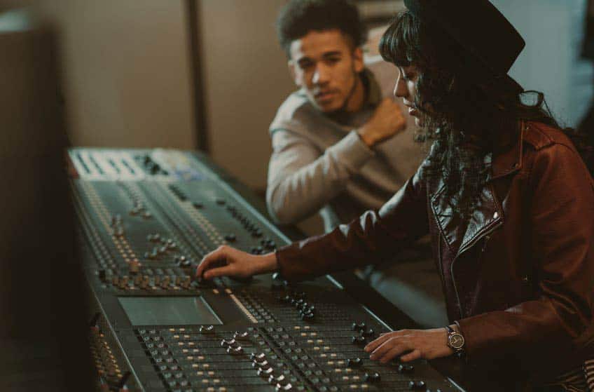 Young female audio engineering student taking music production course at a recording studio
