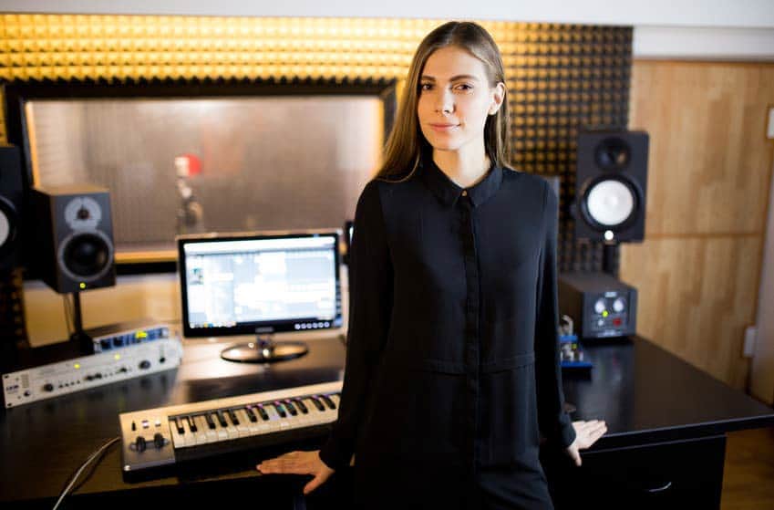 Female music producer in recording studio with computer and monitors