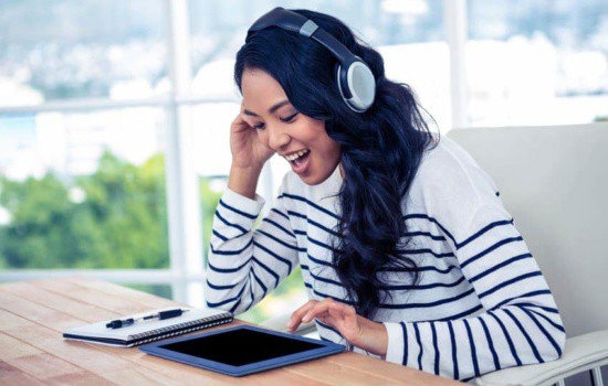 Young female musician using iPad DAW while wearing headphones