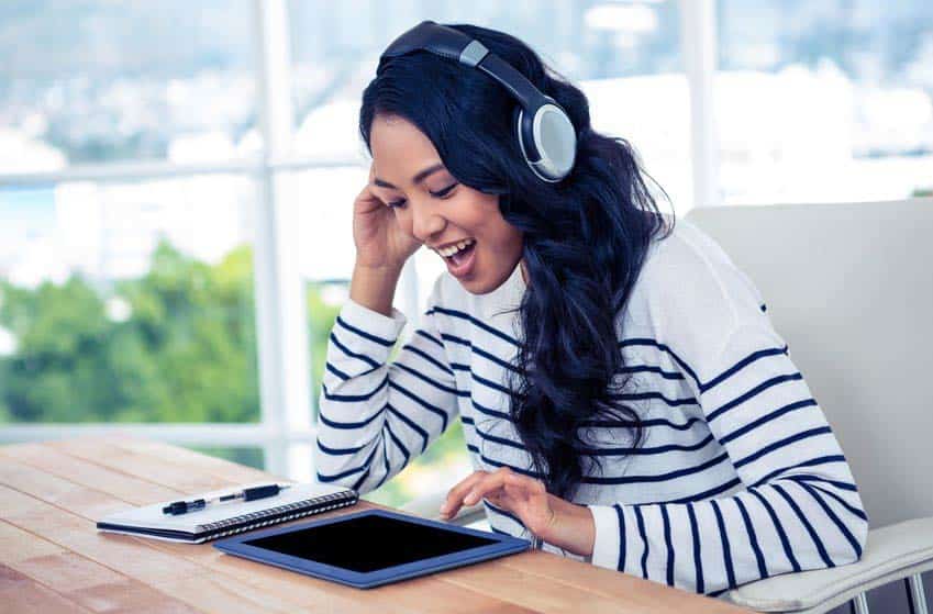 Young female musician using iPad DAW while wearing headphones