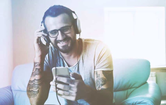 Tattooed young man listening to music on his phone through headphones