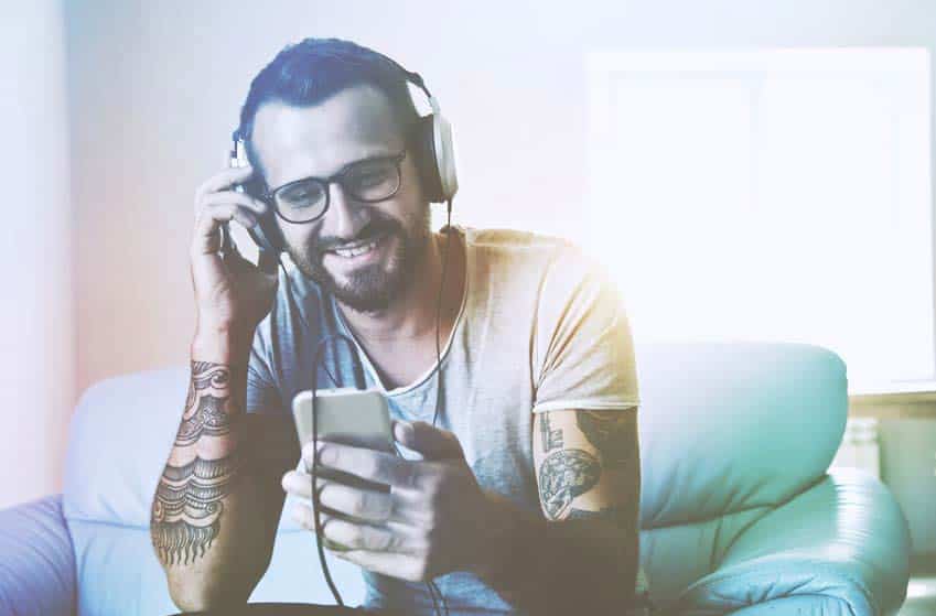 Tattooed young man listening to music on his phone through headphones