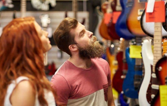 Musical Instrument Sales Representative looking at guitars with music store owner