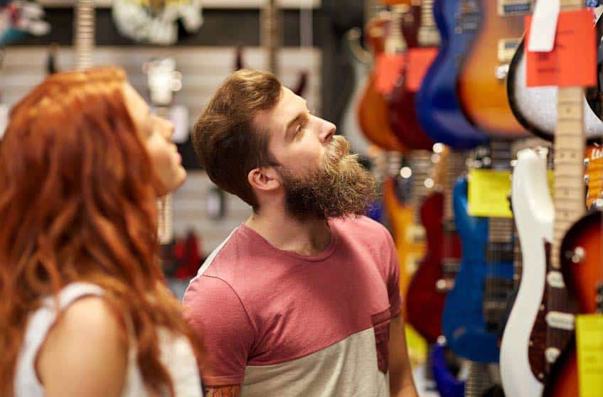 Musical Instrument Sales Representative looking at guitars with music store owner