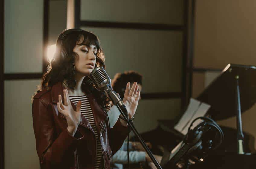 Female singer performing in studio with male piano player