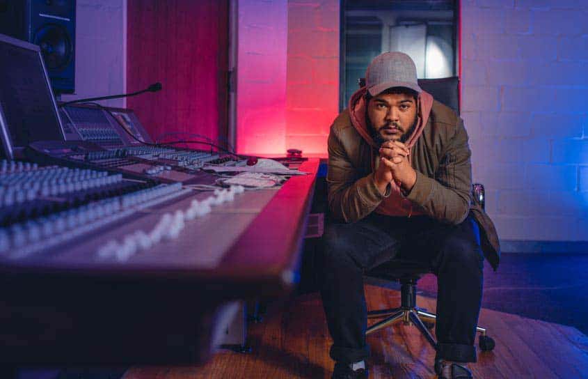 Recording studio manager sitting behind mixing console in recording studio