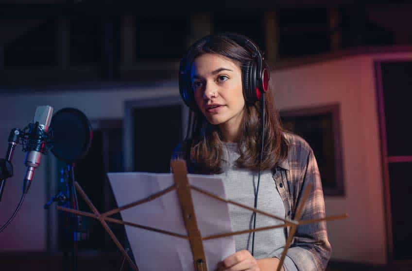 Session singer wearing headphones and looking at sheet music in recording studio