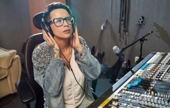 Female audio engineer listening to headphones in home music studio