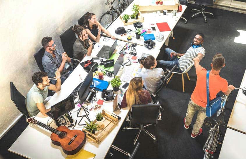 Music company employees sitting around long table with laptops