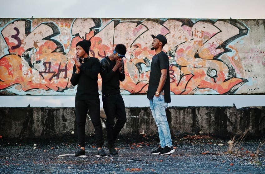 Rappers standing outside graffiti wall