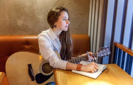 Young woman with guitar writing song lyrics