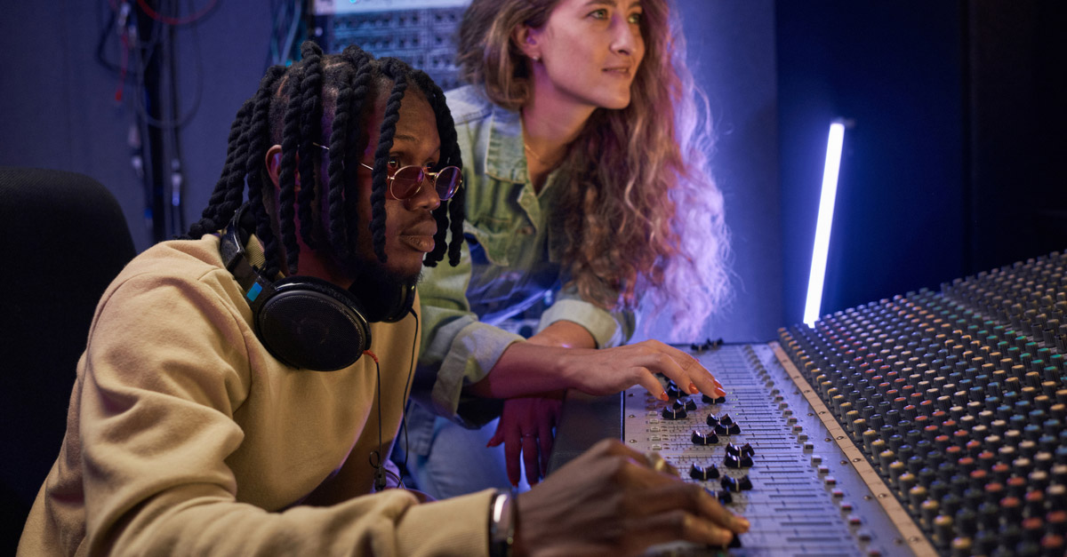 Black male and white female Music Engineers in recording studio