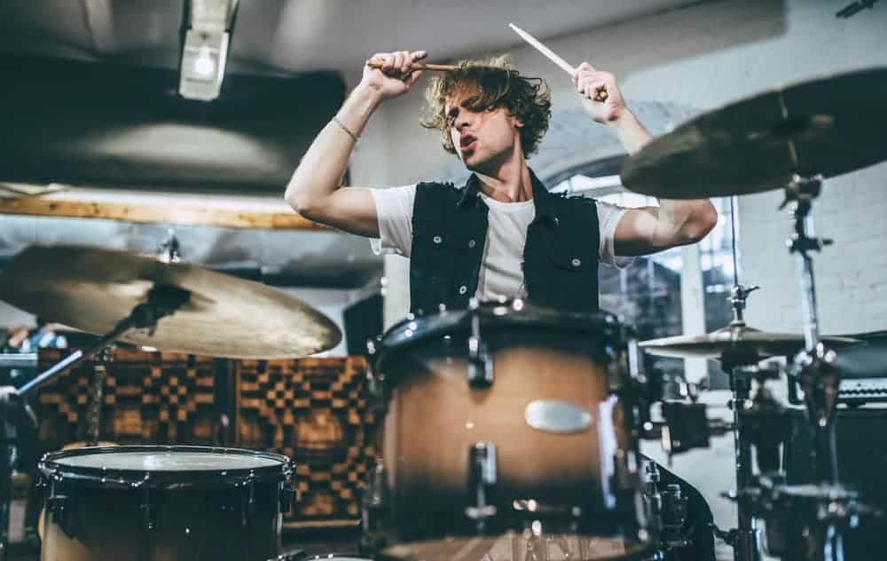 Male drummer playing his kit in rehearsal studio