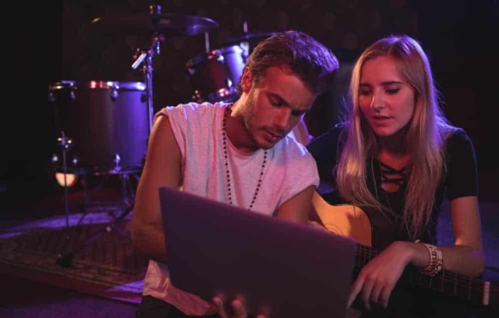 Male and female musician looking at laptop in practice space