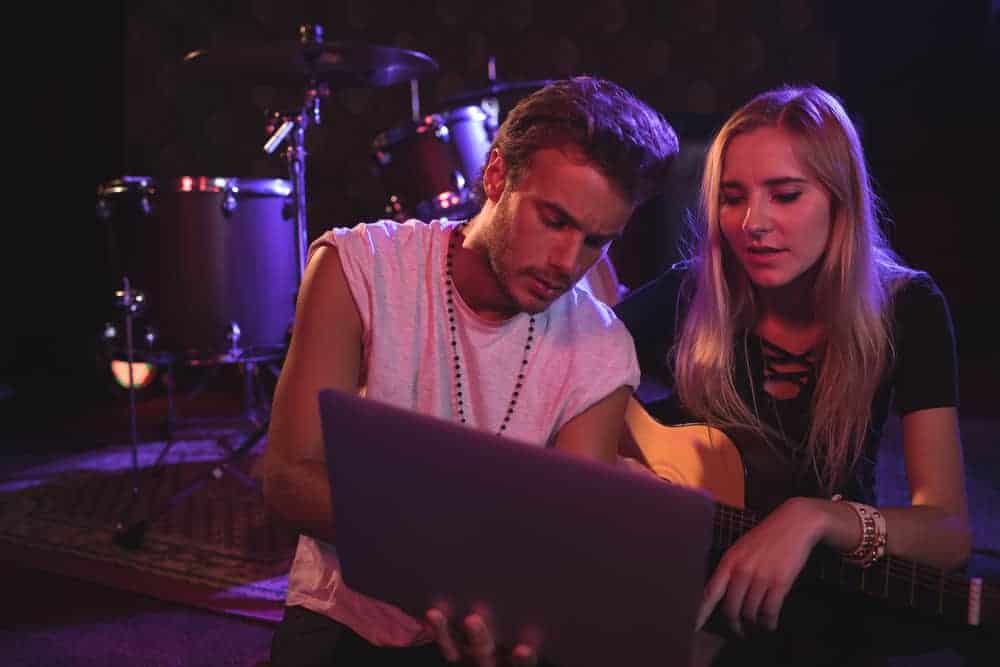 Male and female musician looking at laptop in practice space