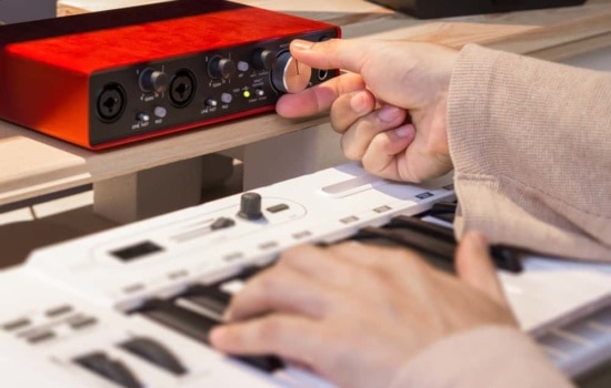 Hand twisting knob on audio interface with keyboard