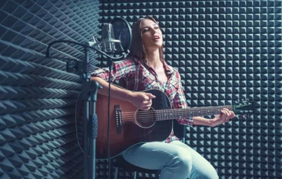 Guitarist with acoustic treatment and microphone in recording booth