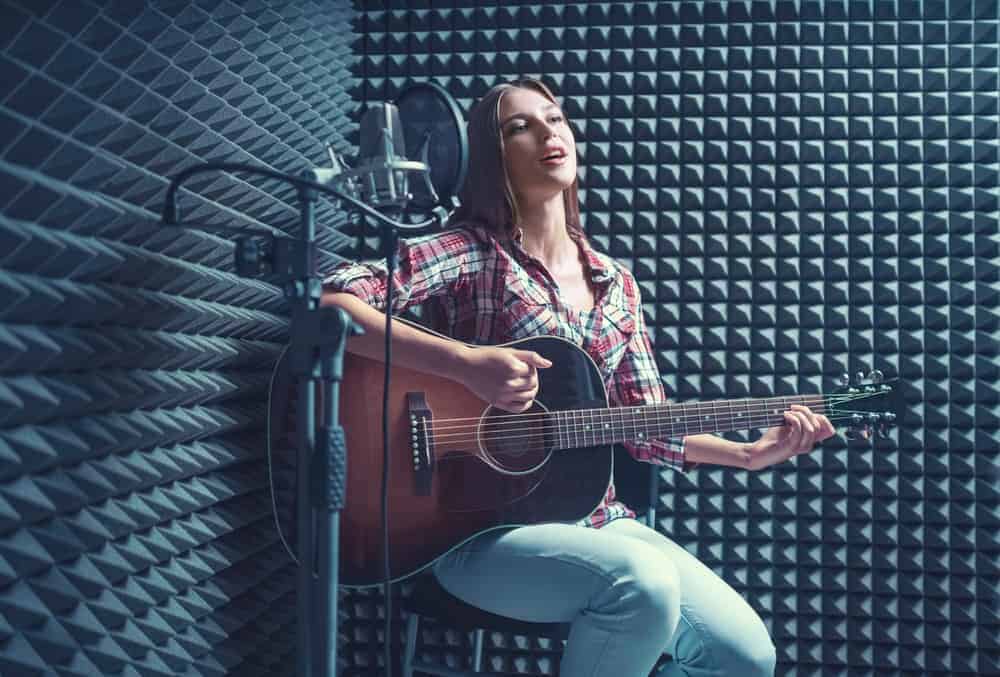 Guitarist with acoustic treatment and microphone in recording booth
