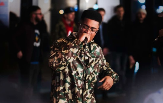 Young black male rapper performing while crowd looks on