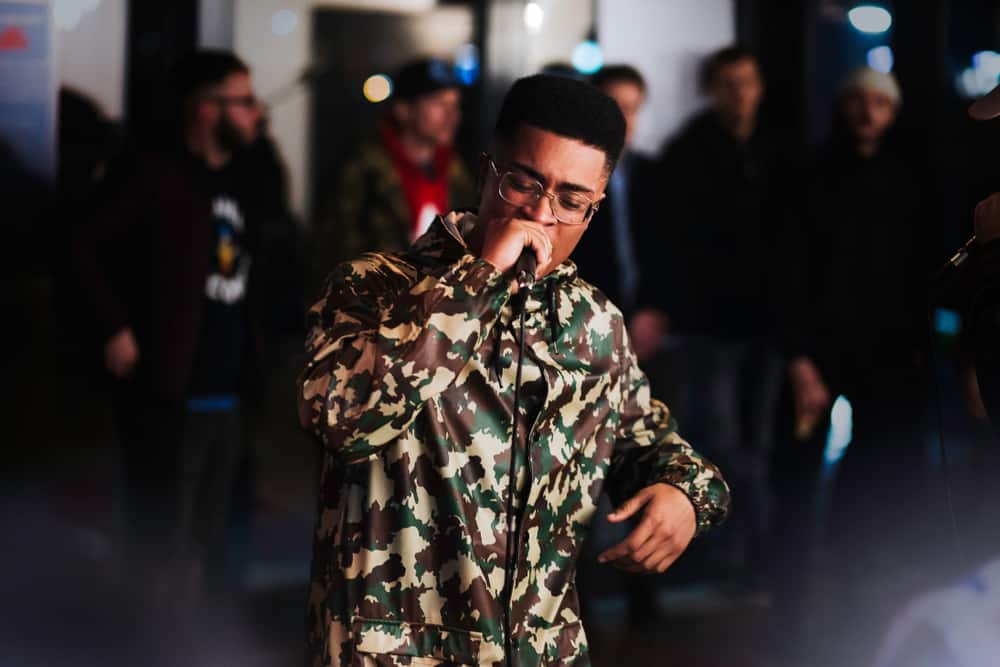 Young black male rapper performing while crowd looks on