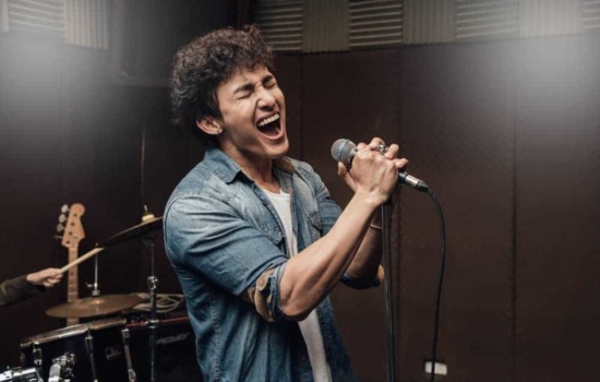 Male recording artist singing into a mic in studio