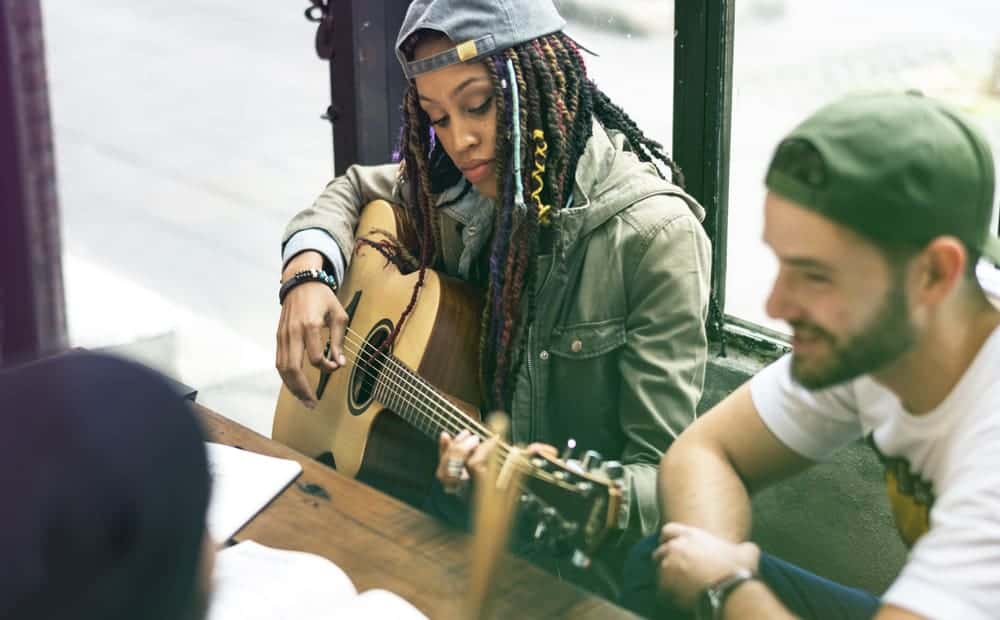Black woman playing guitar with her bandmates