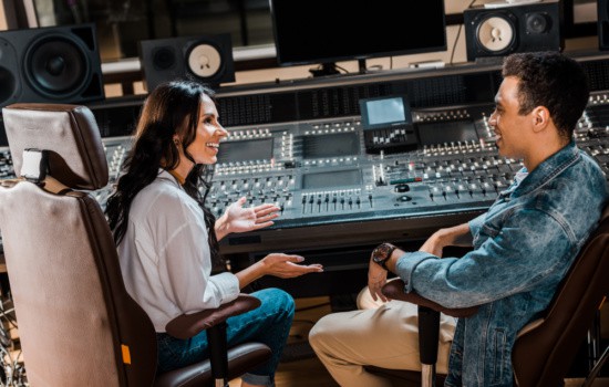 Male and female audio engineers using music technology in recording studio