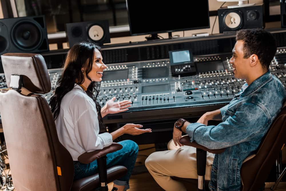 Male and female audio engineers using music technology in recording studio