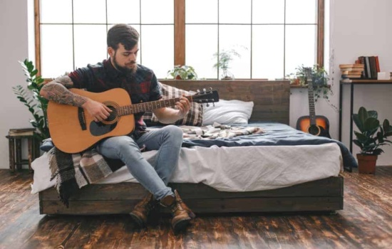 Male musician playing guitar in his room