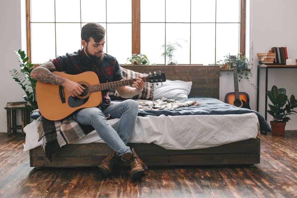 Male musician playing guitar in his room