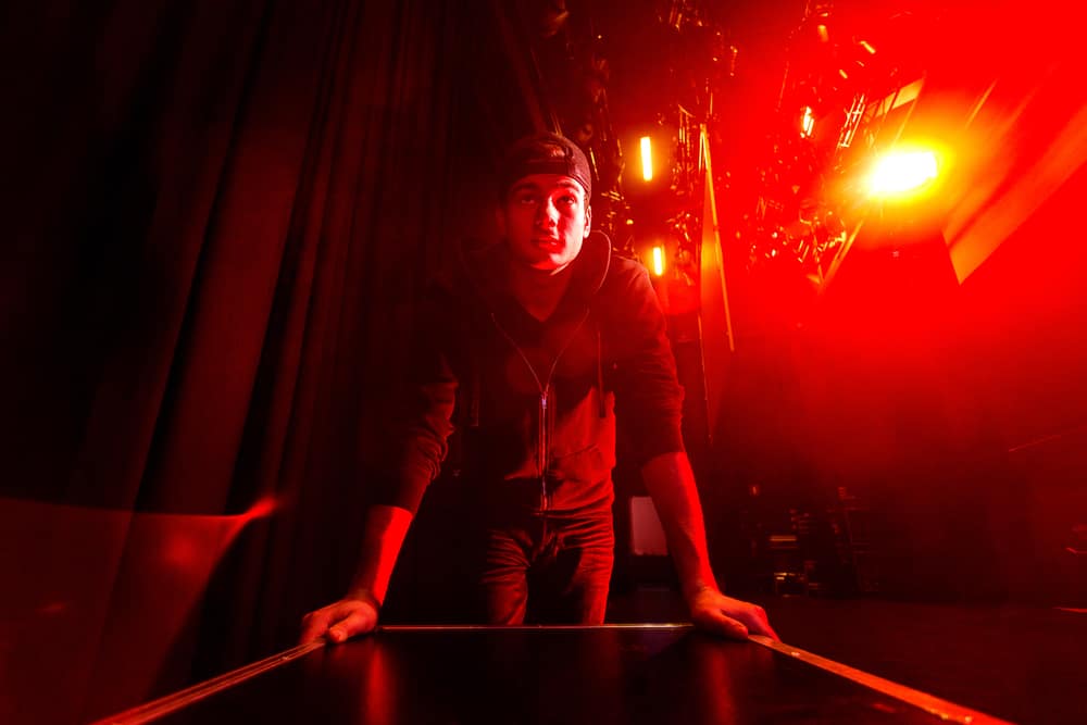 Stagehand transporting musical gear backstage