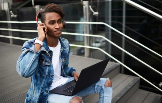 Young male musician using beat making software on his laptop