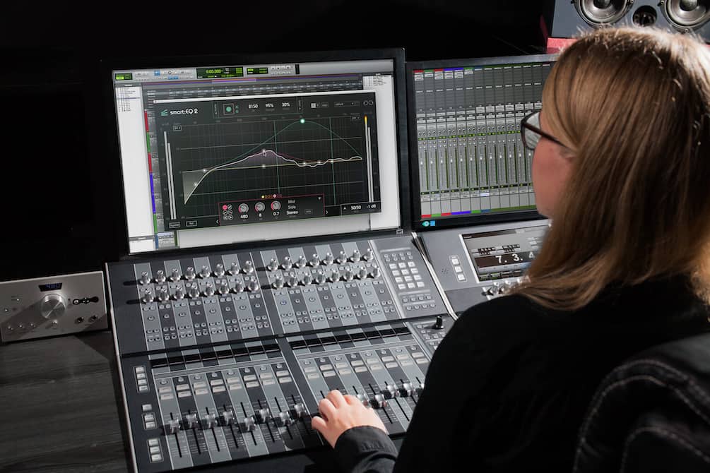 EQ software on computer in recording studio with female audio engineer at the desk