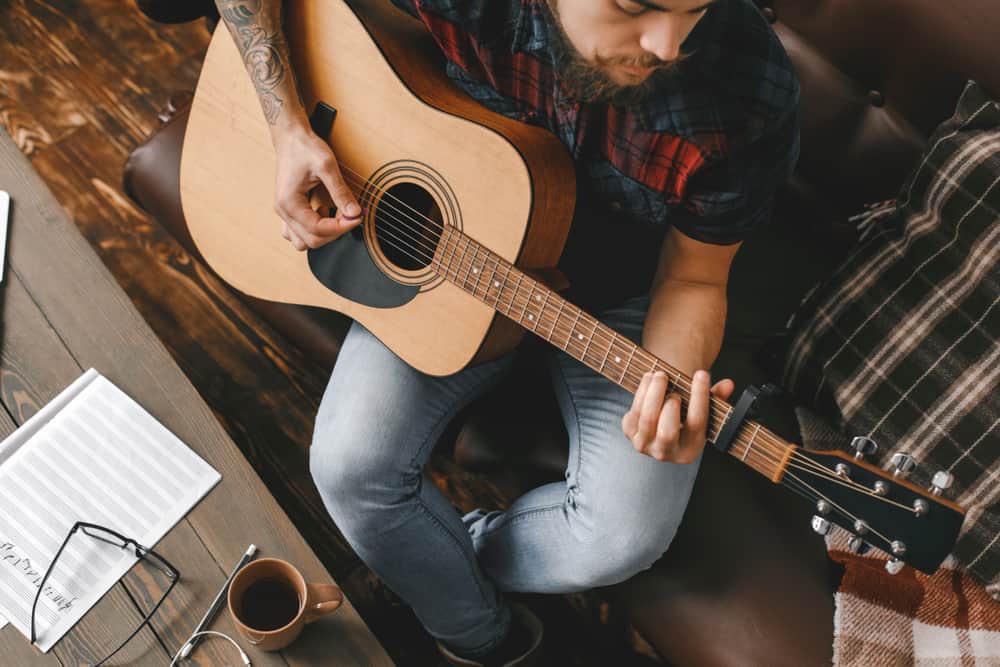 Male musician composing music on his guitar