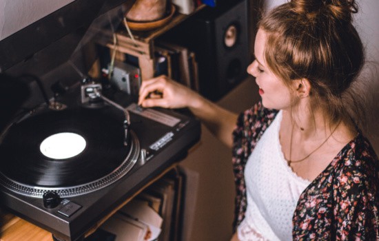 Young woman listening to music on record player