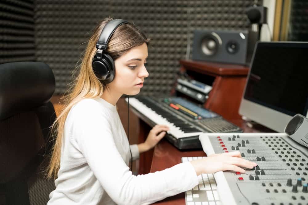 Female audio engineer making music in recording studio