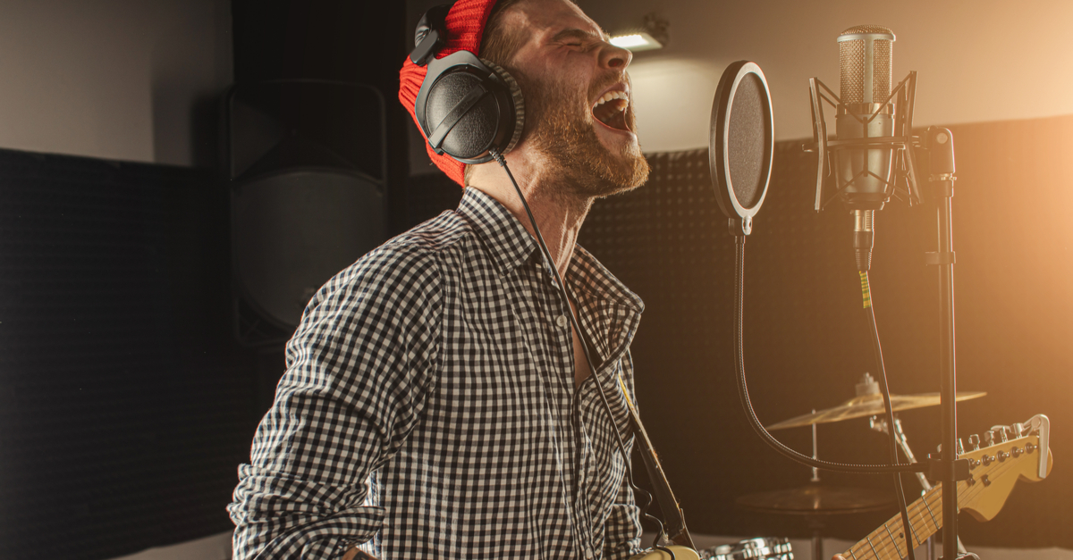 Male singer/guitar player singing at recording studio